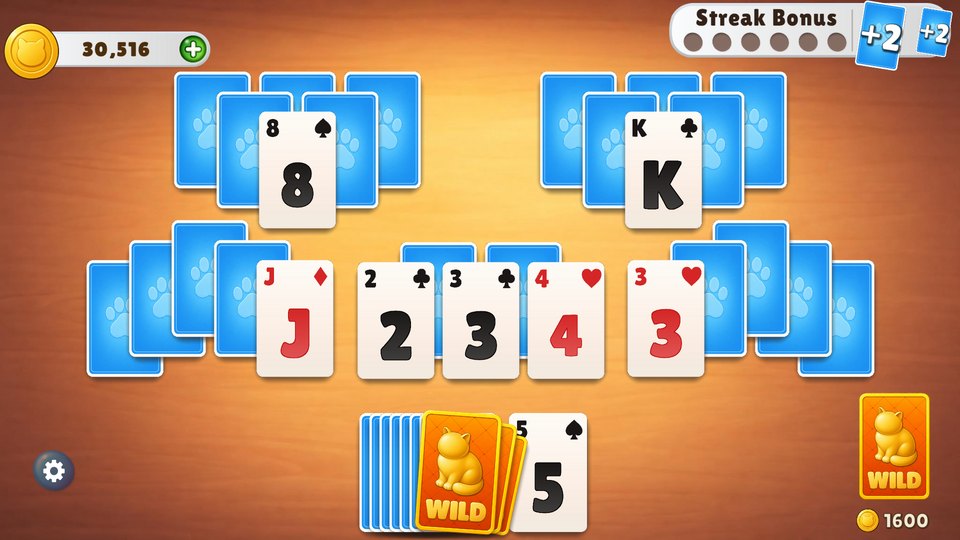 Three Wild Charm cards fanned over a solitaire board